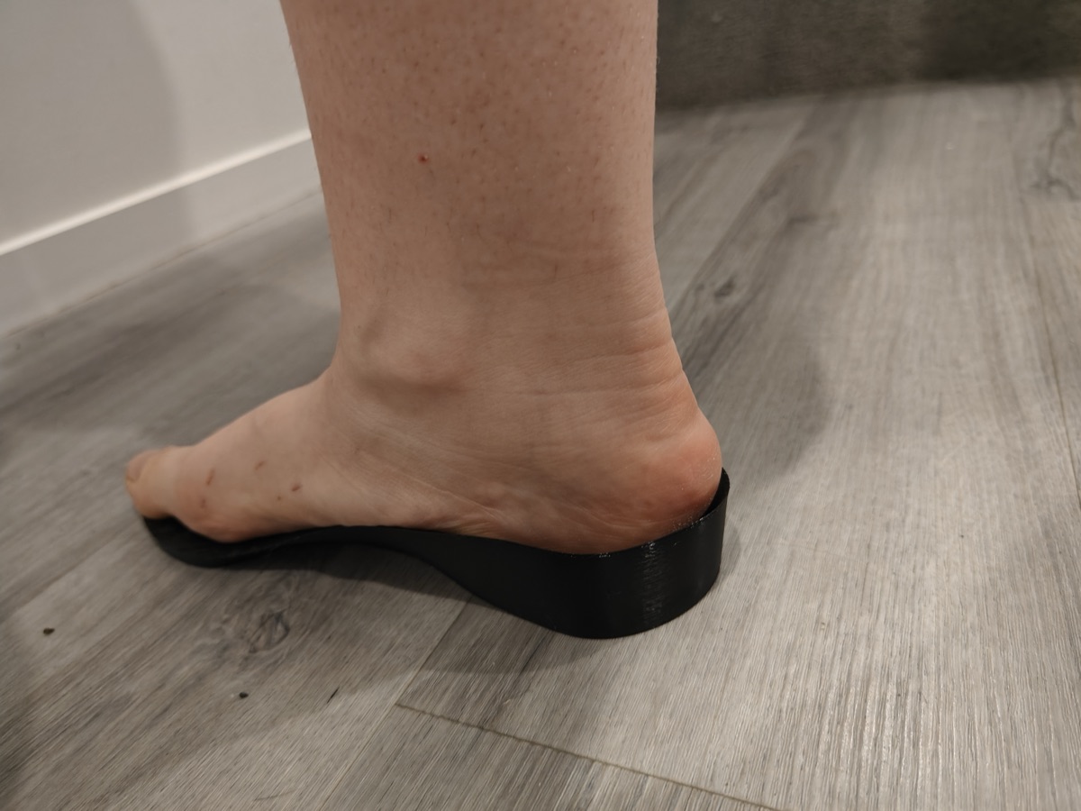 A user's 3D-printed TPU insole supporting the arch, shown in side profile