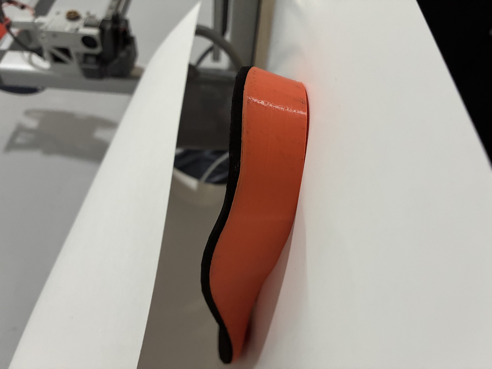 Finished orange and black custom orthotic at a professional fabrication workstation